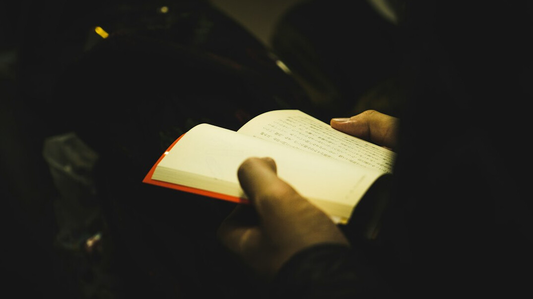 Hand writing in a notebook with a pen on a desk